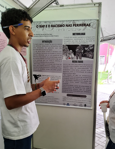 jovem apresentando seu pôster.