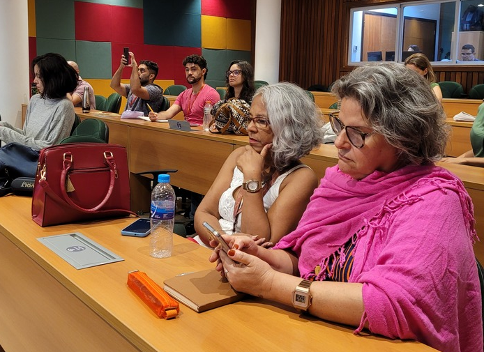 coordenadoras do Observatório Juventude em primeiro plano assistindo à apresentação.