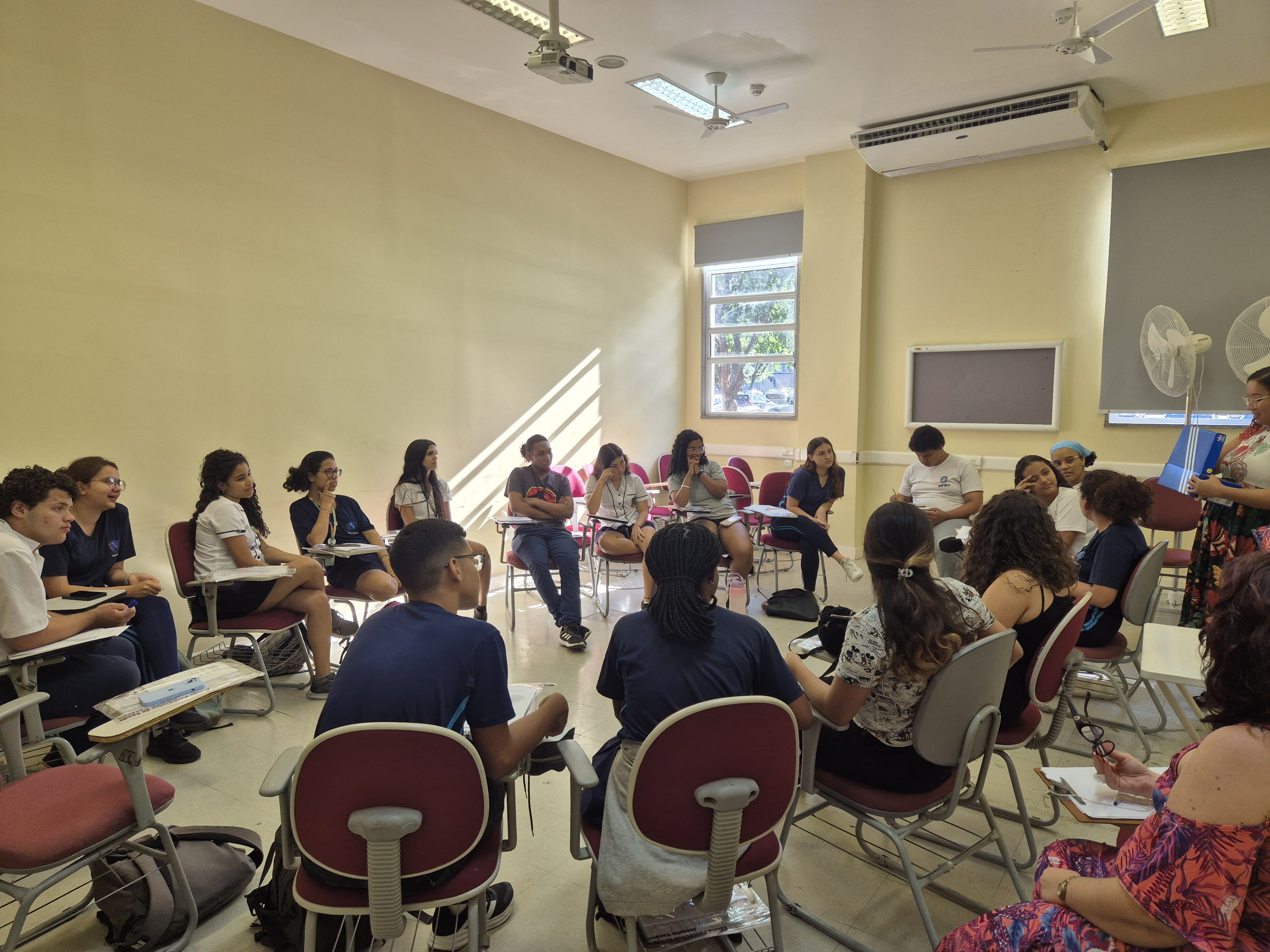 estudantes sentados em semicírculo com as coordenadoras do Provoc.