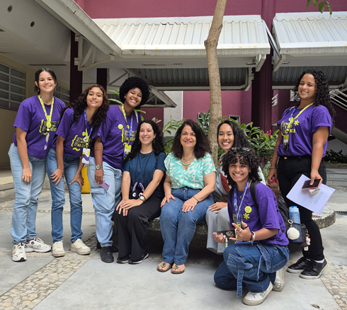 cinco meninas e as três pesquisadoras posam no pátio da Poli para foto.