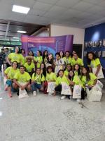 Foto de estudantes e professores sorrindo na frente do poster do evento Mulheres e Meninas na Ciência.