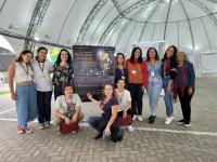 seis alunos posam para foto com parte da equipe do Programa de Vocação Científica, na Tenda da Escola Politécnica.